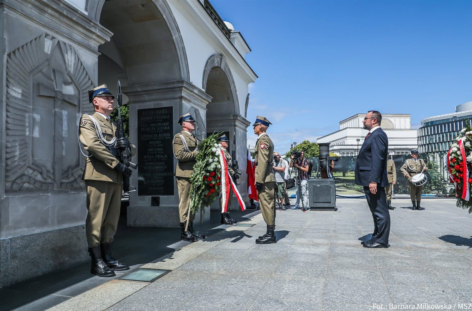 Paweł Jabłoński w postawie zasadniczej przed wartą honorową przy Grobie Nieznanego Żołnierza, obok wieniec ze szarfą Ministra Spraw Zagranicznych